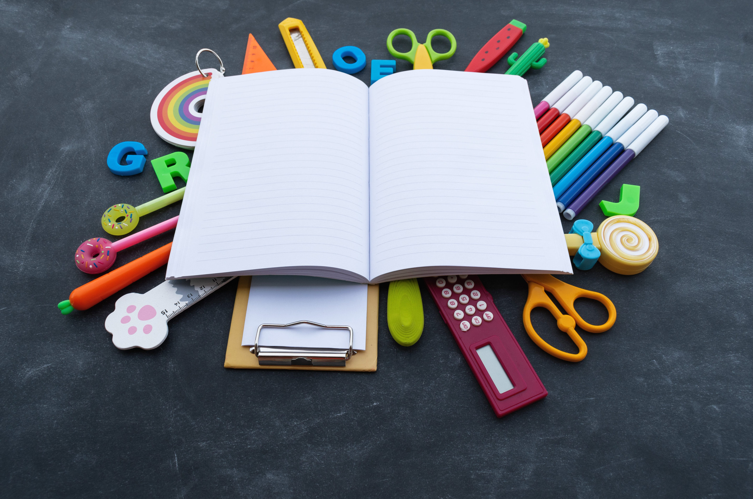 Stationery chalk board. Back to school. Open notepad on top of office supplies. Children stationery for school.